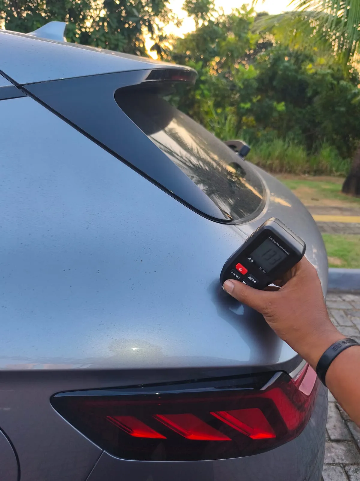 Medidor de espessura de pintura encostado na lateral traseira de um SUV