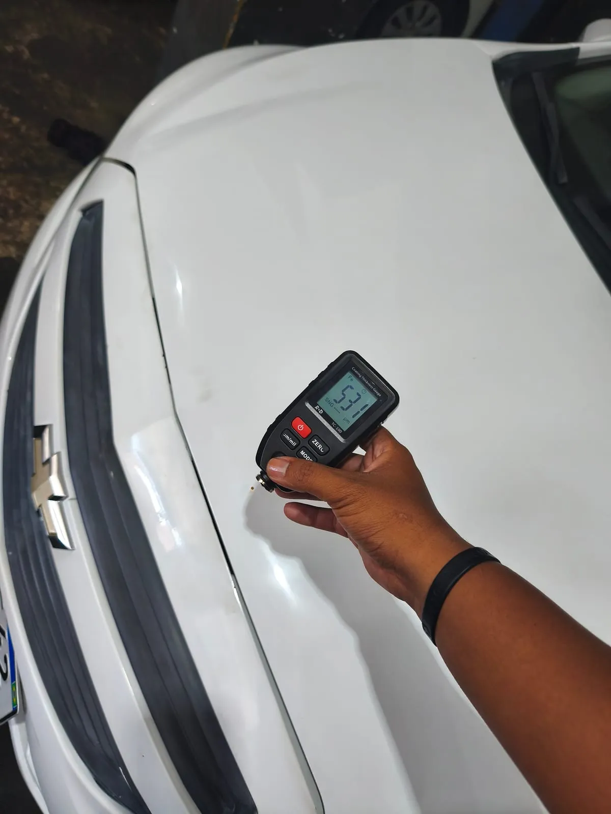 Medição de pintura no para-choque de um carro branco