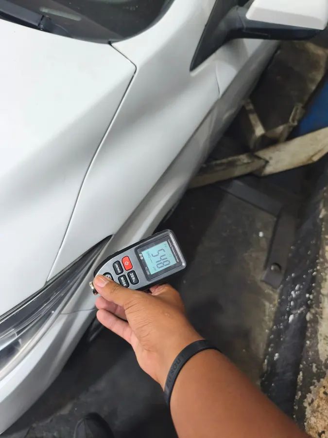 Medidor de pintura na coluna de um carro branco