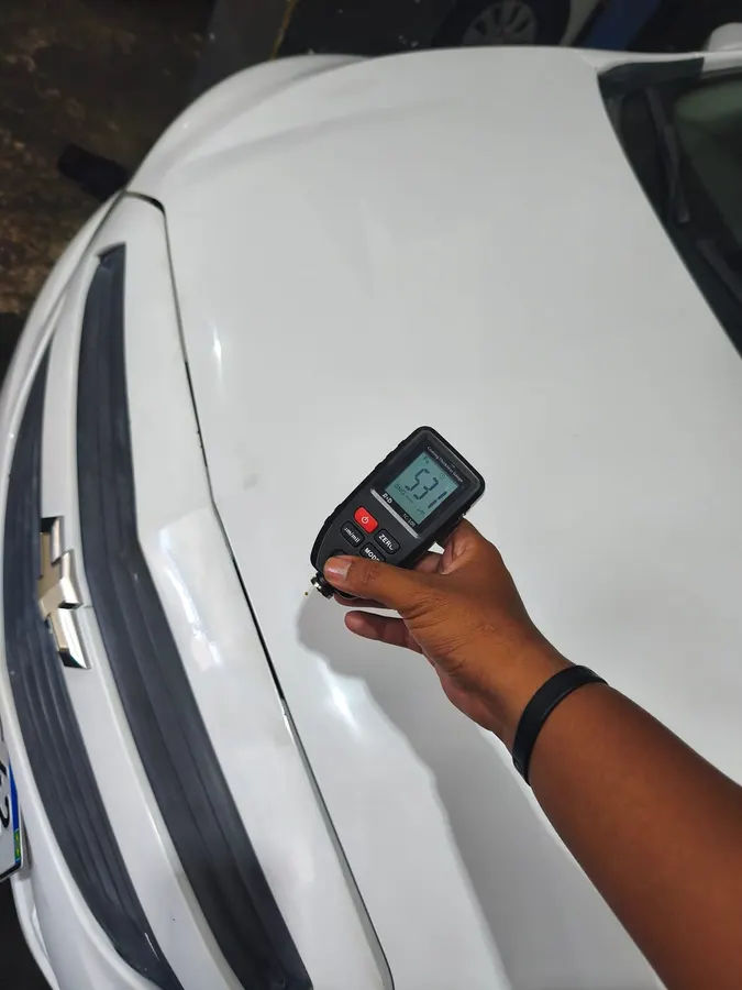 Medição de pintura no para-choque de um carro branco