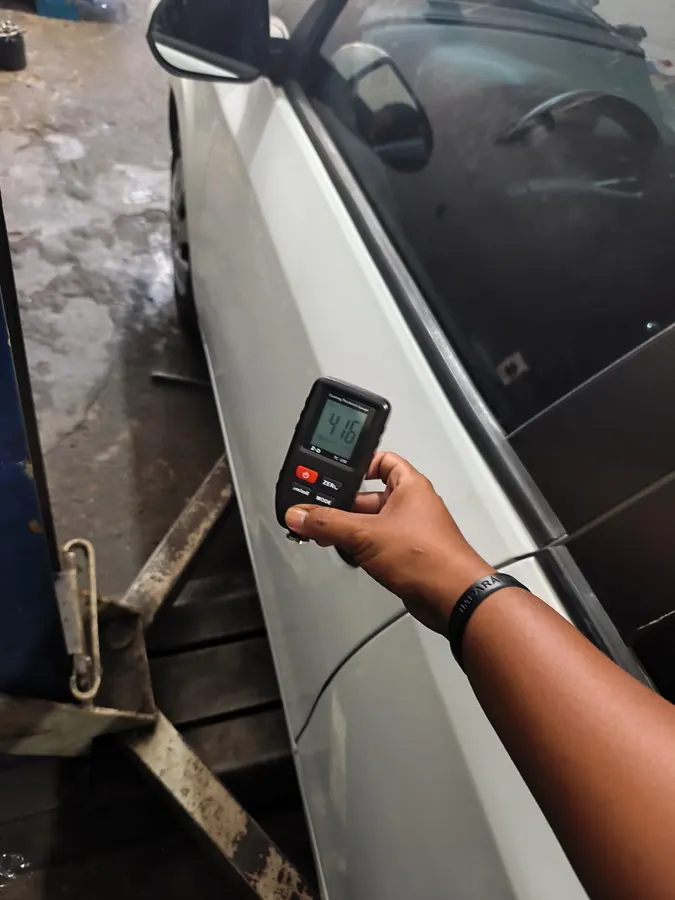 Medição de pintura na porta de um carro branco